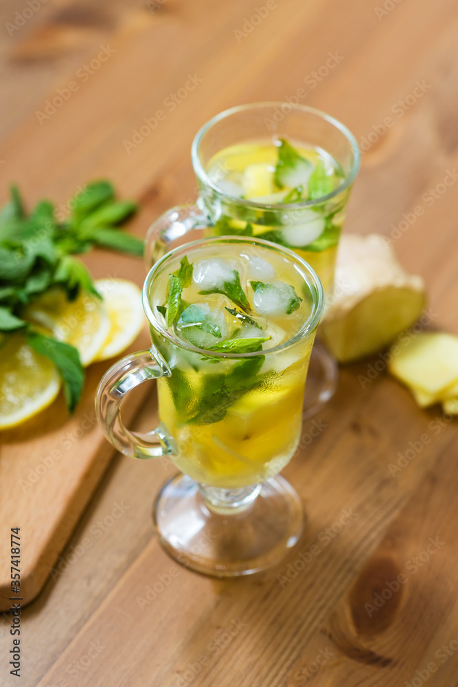 Two glasses with a homemade drink of lemon, mint and ginger