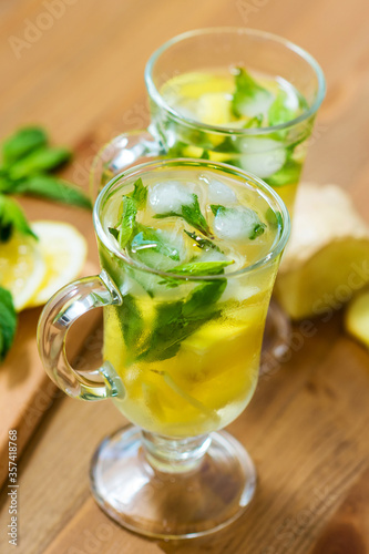 Two glasses with a homemade drink of lemon, mint and ginger