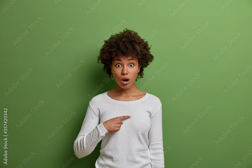 Omg, really me? Confused speechless stupefied woman points at herself, astonished by sudden success, wears white sweater, shocked to be blamed by someone, stands against green studio background Omg, really me? Confused speechless stupefied woman points at herself, astonished by sudden success, wears white sweater, shocked to be blamed by someone, stands against green studio background