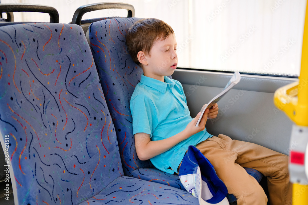 sleeping boy in the bus, with a book in his hands. A child who fell asleep in transport while