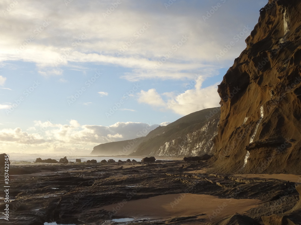 Misty  wreck beach in Victoria, Australia, on a beautiful evening during sunset with the astonishing steep cliffs being illuminated by the last sun rays.