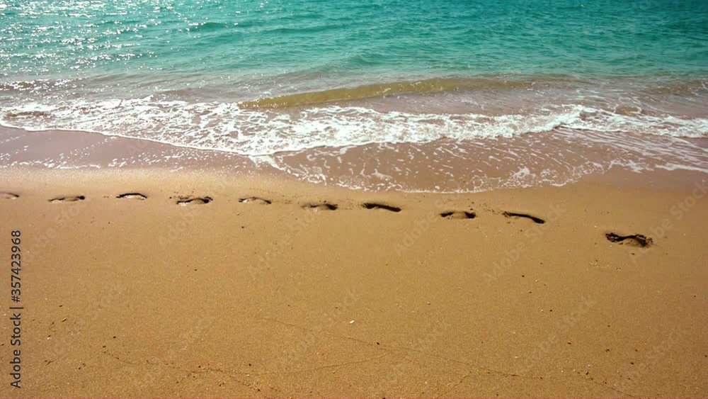 turquoise sea waves slowly wash away human footprints on the yellow sand turquoise sea waves slowly wash away human footprints on the yellow sand