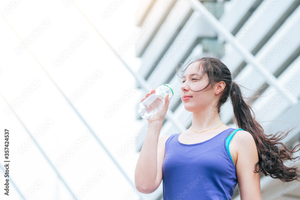 Women drinking water bottle running exercise in modern city wear wellness sportswear outside. Young woman workout outdoor exercising on bright sunny outside. Healthy wellness lifestyle woman concept Women drinking water bottle running exercise in modern city wear wellness sportswear outside. Young woman workout outdoor exercising on bright sunny outside. Healthy wellness lifestyle woman concept