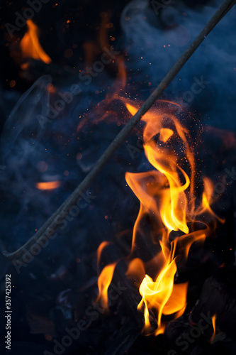 Firewood burns brightly in the grill. Flames of fire close-up.