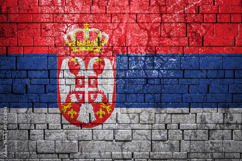 National flag of Serbia on brick wall background.The concept of national pride and symbol of the country. Flag banner on stone texture background.