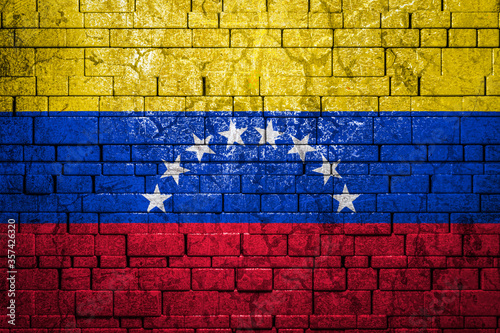 National flag of Venezuela on brick wall background.The concept of national pride and symbol of the country. Flag banner on stone texture background.