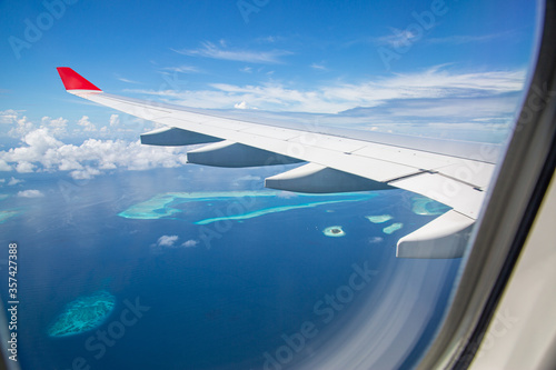 Fototapeta Naklejka Na Ścianę i Meble -  Airplane window with beautiful Maldives island view. Luxury summer holiday travel tourism background, view from airplane window. Atolls and islands with amazing tropical sea