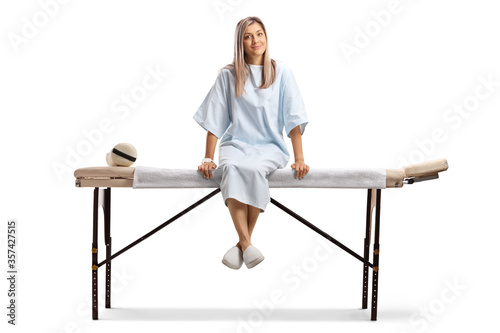 Female patient in a hospital gown sitting on a medical bed