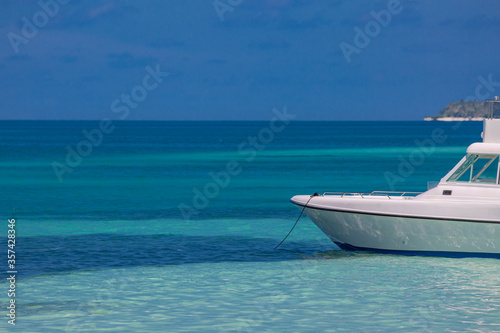 White speed boat in tropical lagoon with island and blue sea background. Snorkel boat in clear ocean waiting for tourist going for excursion  © icemanphotos
