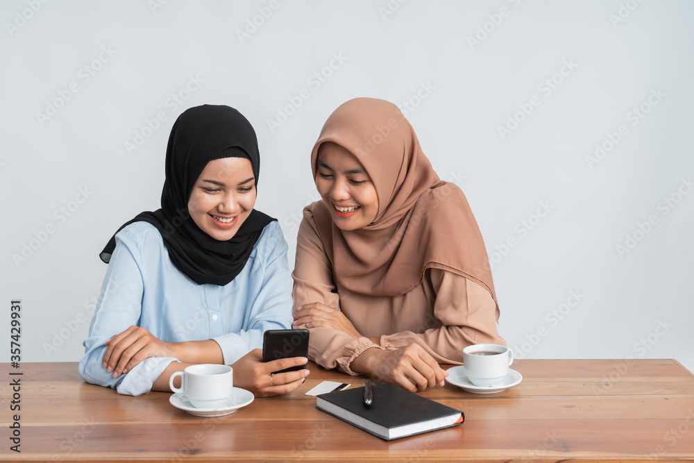 muslim bestfriend gossiping on social media using mobile phone muslim bestfriend gossiping on social media using mobile phone
