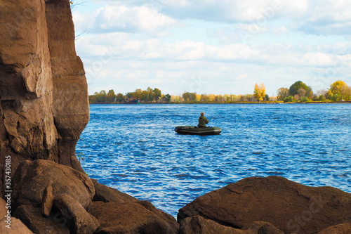 Fisherman in an inflatable boat on the river in the autumn. Kama River, Russia