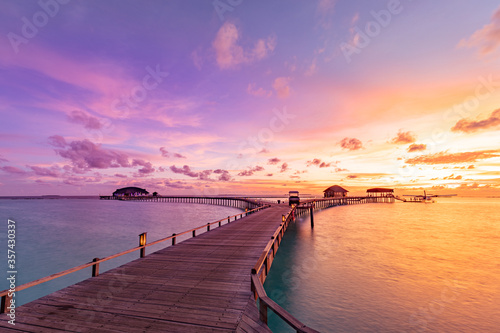Amazing sunset sunrise sky and reflection on calm sea  Maldives beach landscape of luxury over water villas bungalows. Exotic scenery of summer vacation and holiday background. Tropical seascape sky