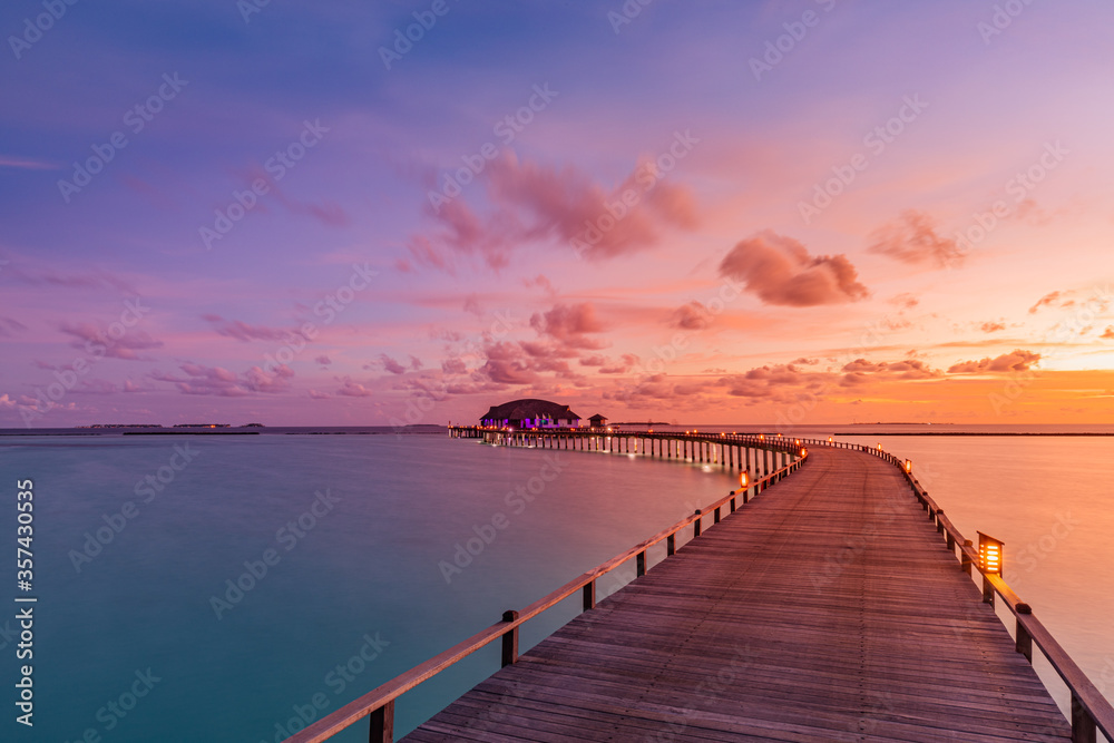 Amazing sunset sunrise sky and reflection on calm sea, Maldives beach landscape of luxury over water villas bungalows. Exotic scenery of summer vacation and holiday background. Tropical seascape sky