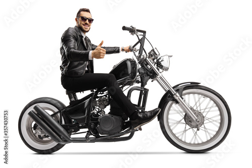 Biker on a custom chopper riding and showing thumbs up
