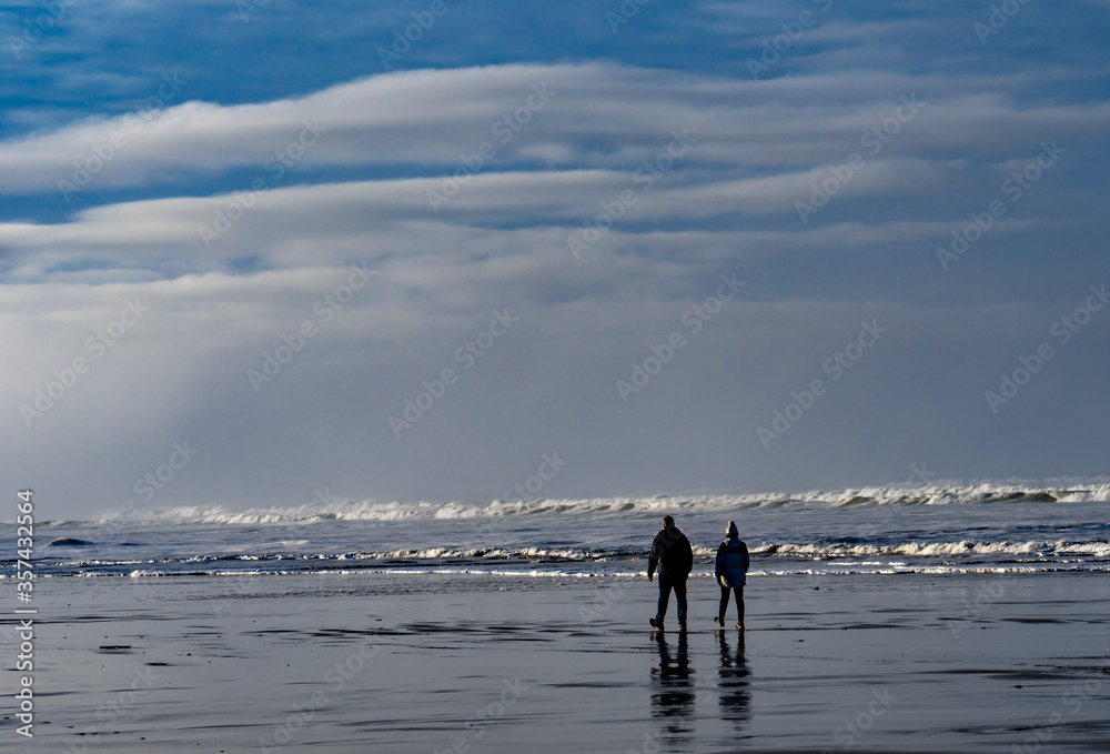 A man and woman walking on the beach at Canon Beach, Oregon