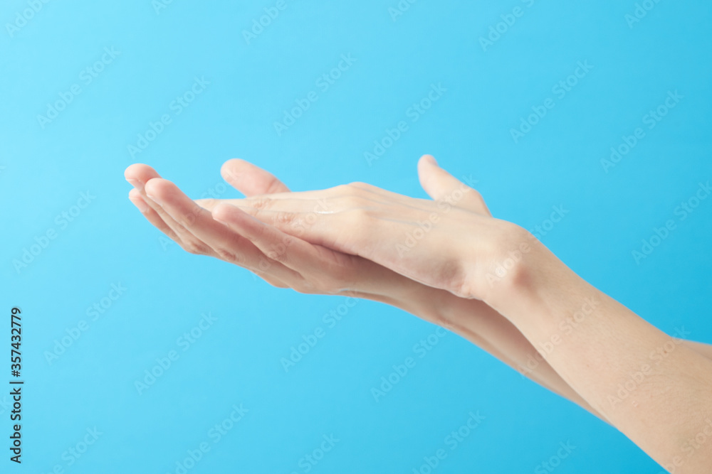 Close up woman hands using wash hand sanitizer gel in blue background.