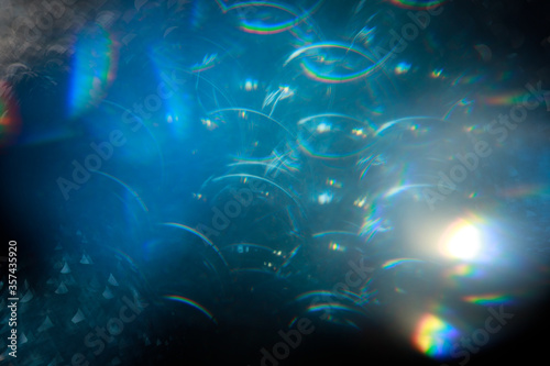 Easy to add lens flare effects for overlay designs or screen blending mode to make high-quality images. Abstract sun burst, digital flare, iridescent glare over black background. © KDdesignphoto