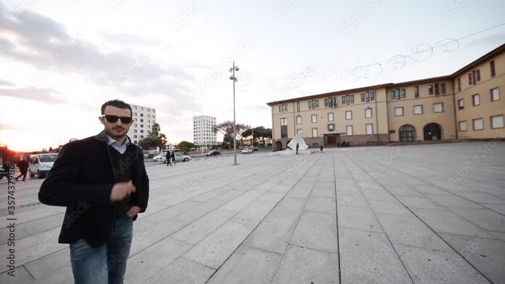 ragazzo moro con giacca e occhiali scuri, gira per una piazza nel centro di una città ragazzo moro con giacca e occhiali scuri, gira per una piazza nel centro di una città