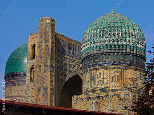 Portal and one of buildings of famous cathedral Mosque of Bibi Khanym, one of popular tourist sights in Samarkand, Uzbekistan. All of buildings richly decorated with traditional eastern ornaments. photo