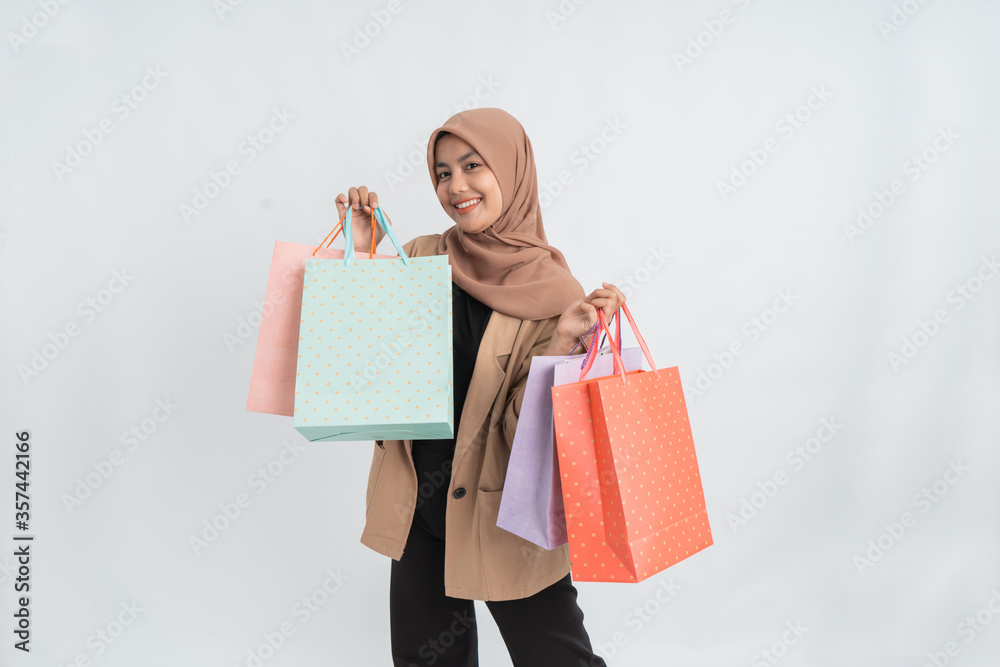 excited young muslim woman shopping holding paper bag in her hand over white background
