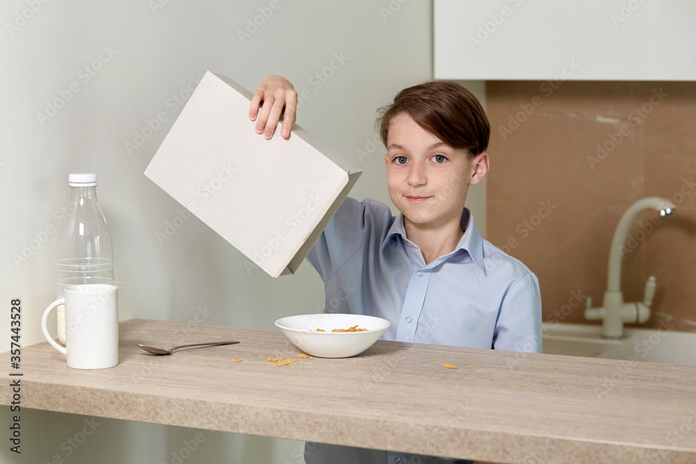 Brunette boy is preparing breakfast for himself. Pour cereal into a plate. Brunette boy is preparing breakfast for himself. Pour cereal into a plate.