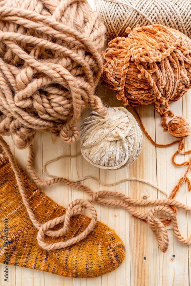 The yarn is beige, brown and light brown. Background of light wood. 