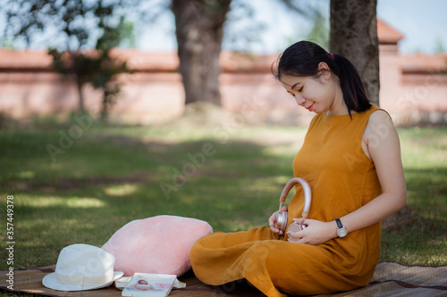 Yung Pregnant woman listening music in the park.