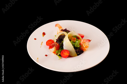 Salad with prawns, cheese, lettuce, tomatoes. Black background