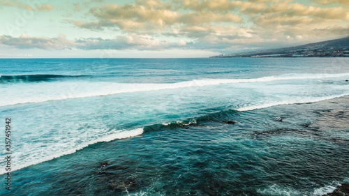 Aerial oceanand coastline view - sea water and surf waves and sky with clouds at the horizon in background - tourism and coast scenic place for vacation