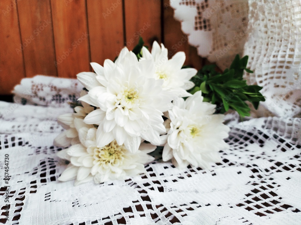 Bouquet of white chrisanthemums on a white lace tablecloth