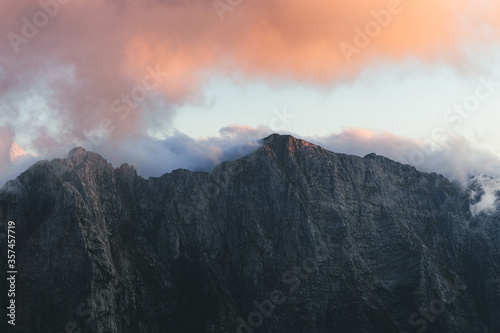 Low angle view of rocky mountains against colorful sunset or sunrise. Top mountain view on Mangart Pass, Julian Alps, Slovenia