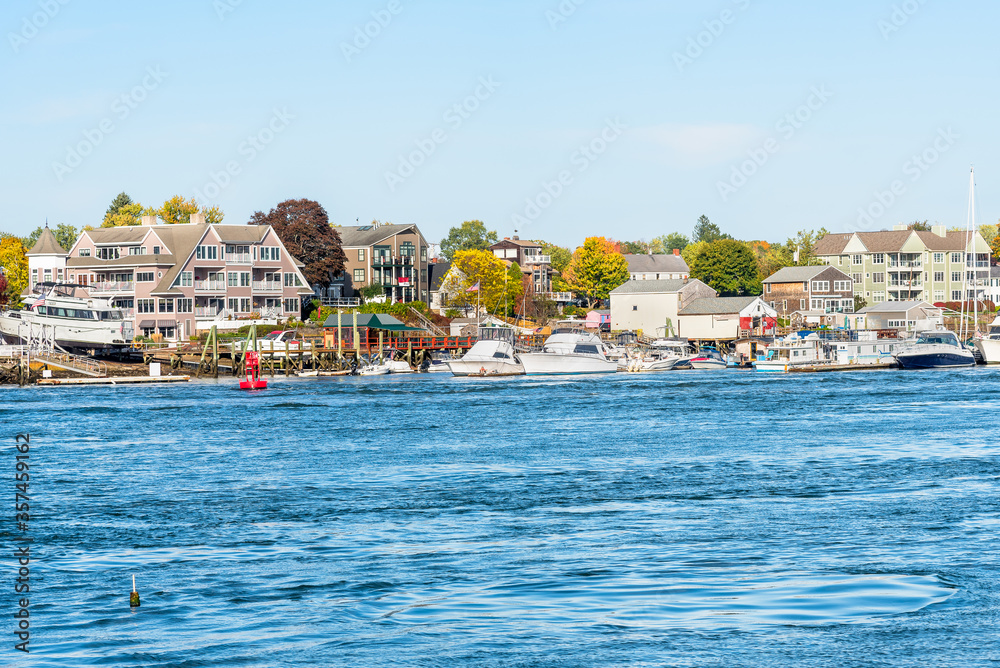 Marina along a might river with residential buildings in background on a clear autumn day. Kittery, ME, USA. Marina along a might river with residential buildings in background on a clear autumn day. Kittery, ME, USA.