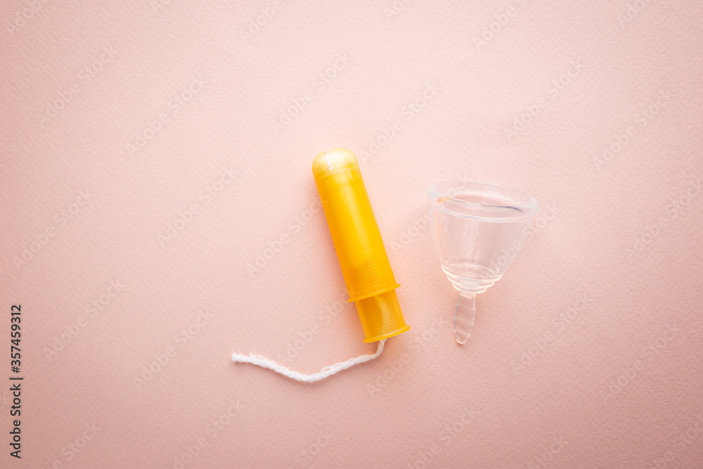 Menstrual cup on pink background. Alternative environmentally friendly feminine hygiene product to collect blood during the period inside the vagina.