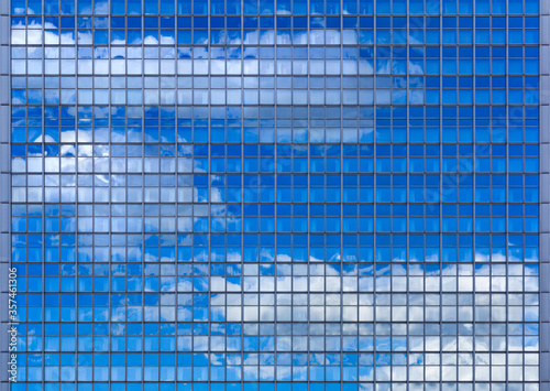 Wolken spiegeln sich in der Glasfassade eines Hochhauses