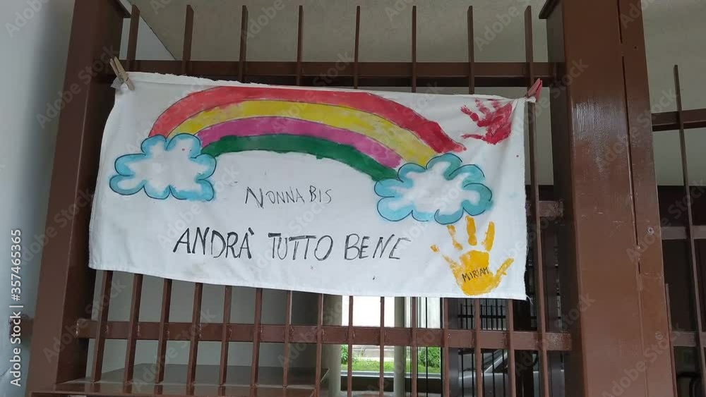 Turin, Piedmont, Italy. June 2020. Coronavirus pandemic. On the facades of the houses hang the sheets with the drawing of the rainbow and message everything will be fine. In Italian 
