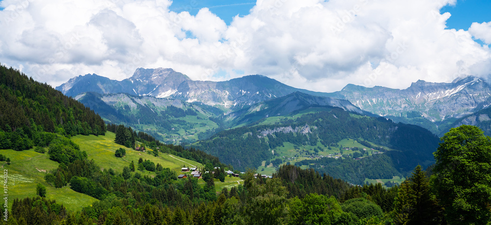 Obraz premium Amazing summer panorama with mountains, small village, green meadows and cloudly blue sky in Swiss Alps. Oberland, Switzerland.