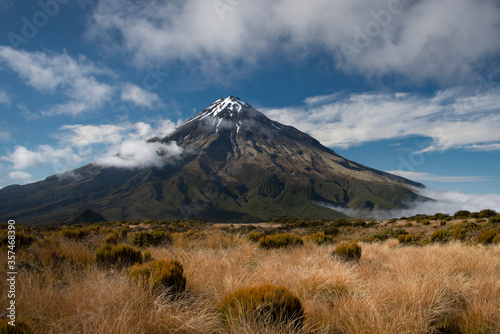 Mount Taranaki among the drifting clouds with tussocks in the foreground