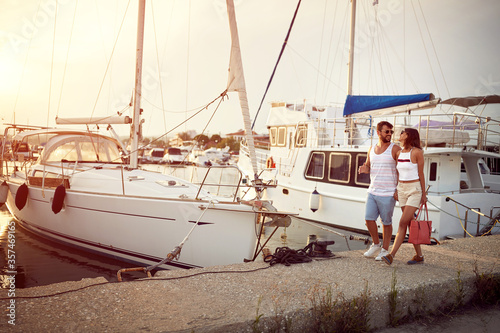Couple in love walking on the dock going on yacht at vacation.