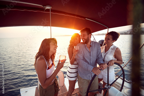 Young people drinking on a yacht and enjoying at vacation and luxury travel at sunset. © luckybusiness