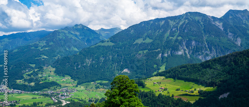 Panoramic view of idyllic scenery near Lake Lungern with fresh green meadows. Beautiful sunny day in springtime in Switzerland. Summer rural view. Village in green mountain valley.