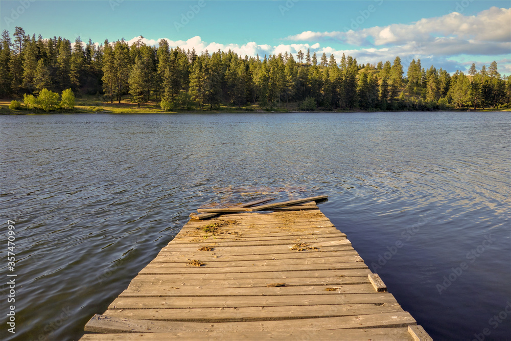 wooden dock on a tranquil lake with blue skies and evergreen trees in British Columbia, Canada wooden dock on a tranquil lake with blue skies and evergreen trees in British Columbia, Canada