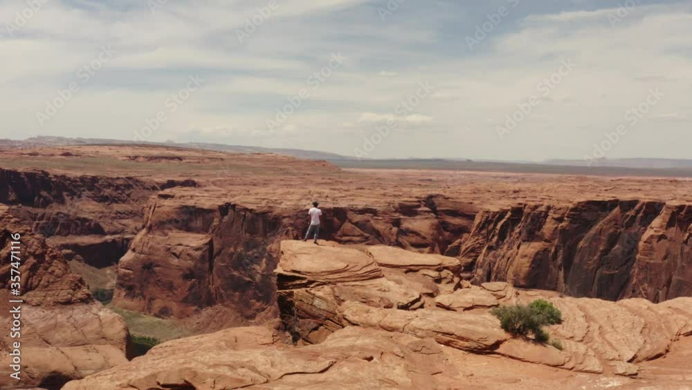 Travel photographer standing on the edge of Horseshoe Bend, a river in canyon, scenic Arizona