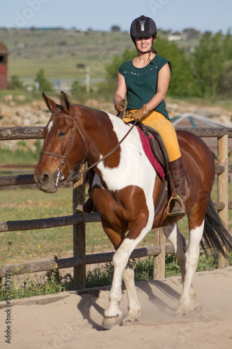 Side view of happy female horse rider riding a palomino mare.