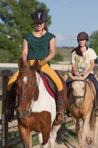 Sisters with happy actitude at a horse riding lesson.