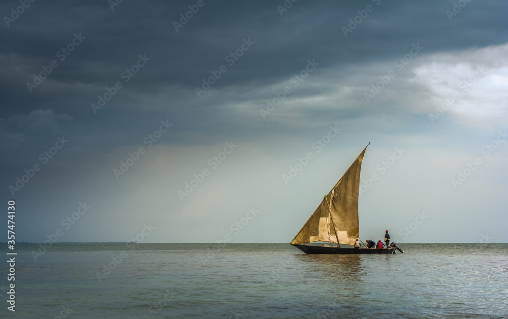 Dhowboat sailing into rainstorm off the coast of Tanzania, locals fishing