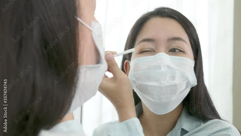 Mirror reflection asian woman wear surgical face mask apply cosmetic make up for go out to work after unlock Coronavirus lockdown. Reopenning , restart, Self-quarantine and social distancing concept. Mirror reflection asian woman wear surgical face mask apply cosmetic make up for go out to work after unlock Coronavirus lockdown. Reopenning , restart, Self-quarantine and social distancing concept.
