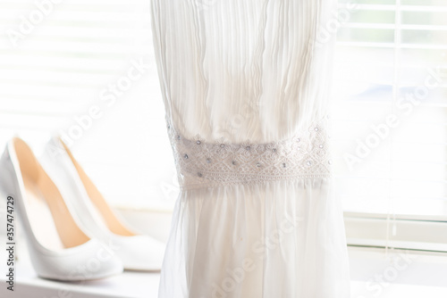 white shoes and a dress are for the bride against the background of a bright window with jalousie
