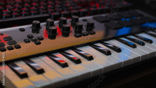 keyboard of musical synthesizer or midiclevia in an amateur recording studio, the keyboard reflects the monitor and other lighting of the studio