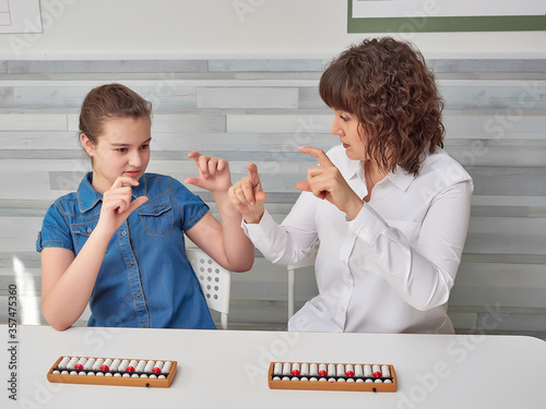 Classes in mental arithmetic, the teacher teaches the child mental counting in additional classes in mental arithmetic. abacus soroban are on the desk. copy space.