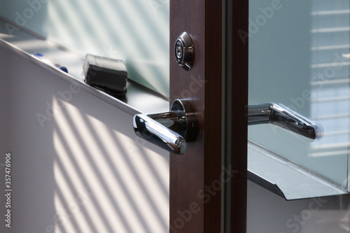 Close-up of glass door handle by white board